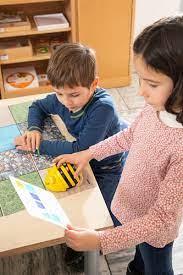 Schatzinsel Coding: Kinder programmieren den Bee-Bot anhand einer Aufgabenkarte. KiTa-Spielewelt