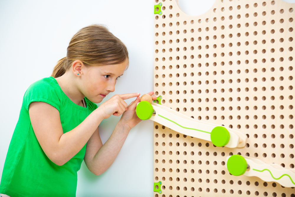 PLU IT Kugelbahn-Set: Ein Mädchen in einem Kindergarten spielt mit einer Kugelbahn an einer Lochwand.