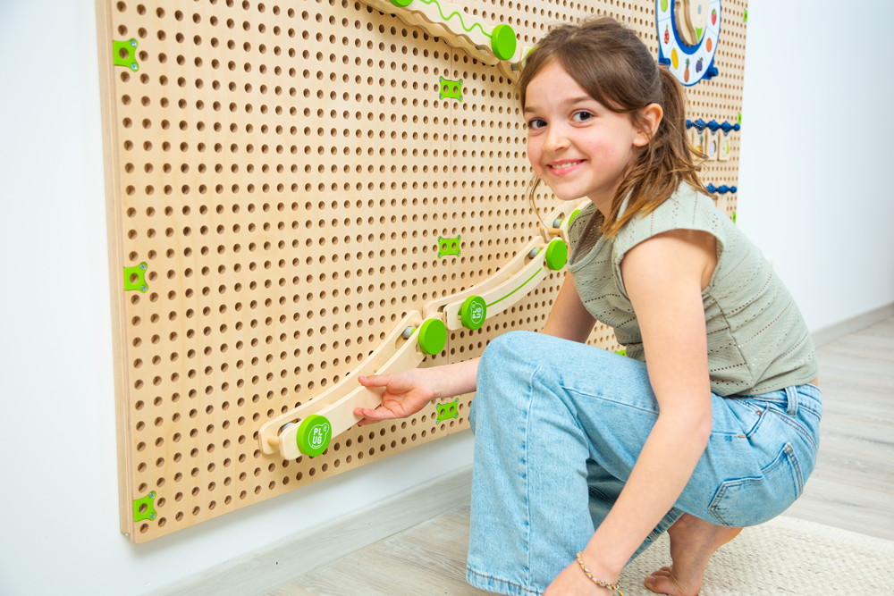 PLU IT Kugelbahn - Set -Ein Mädchen in einem Kindergarten spielt mit einer Kugelbahn an einer Lochwand